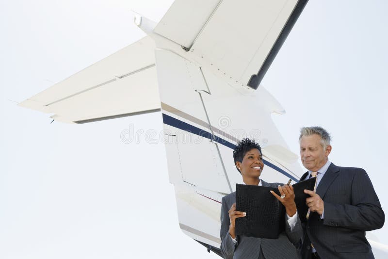 Confident multiethnic business people discussing below wing of private jet