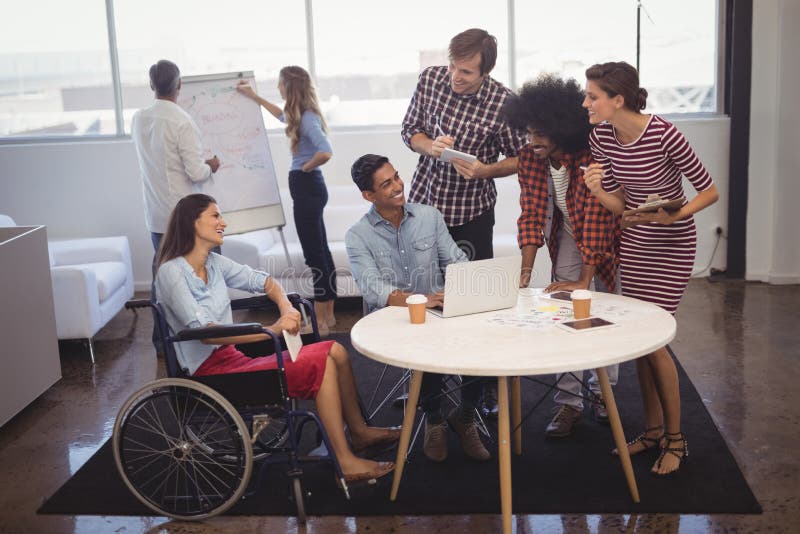 Business people discussing strategies with disabled colleagues in creative office stock photography Business people discussing strategies with disabled colleagues in creative office stock photography