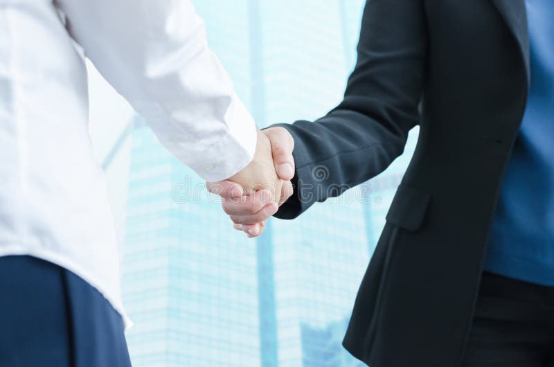 Business people shaking hands, finishing up a meeting with modern building background. royalty free stock photo Business people shaking hands, finishing up a meeting with modern building background. royalty free stock photo