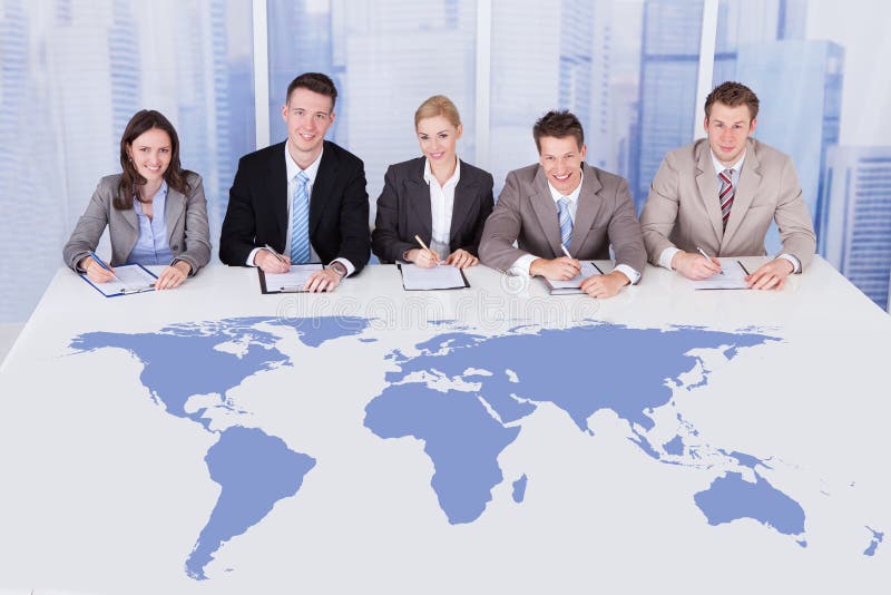 Business people sitting at conference table with world map