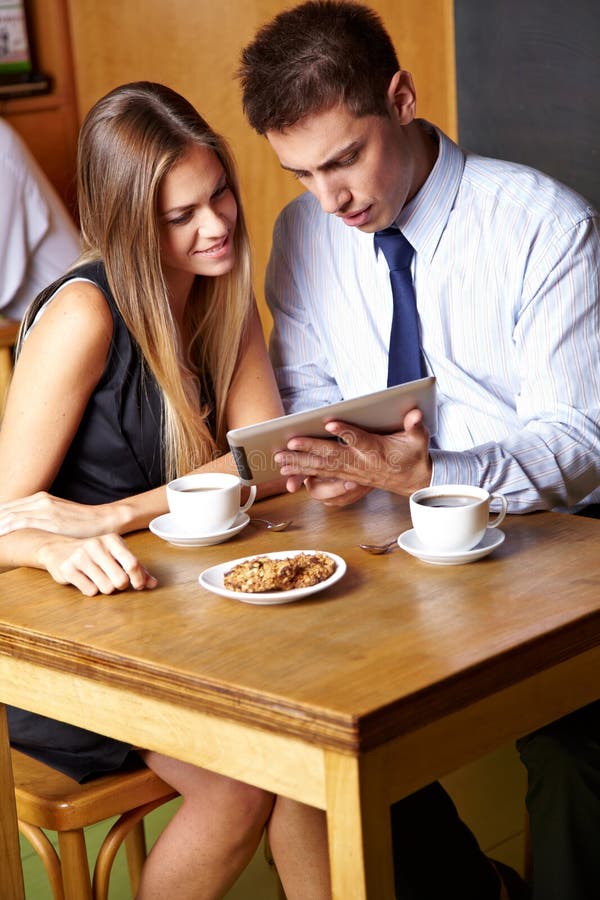 Two business people working with tablet computer in a cafÃ©. Two business people working with tablet computer in a cafÃ©