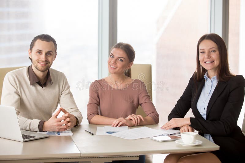 Business people team sitting at office desk looking at camera royalty free stock photo Business people team sitting at office desk looking at camera royalty free stock photo