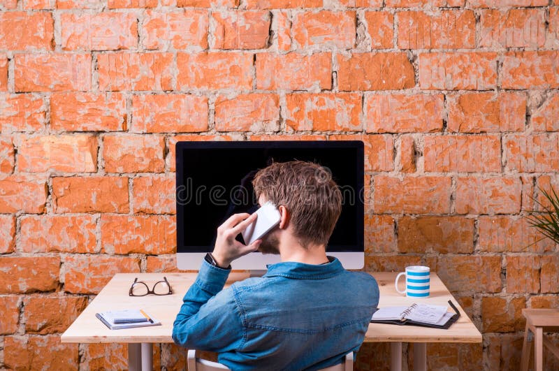 Business person sitting at office desk, talking on phone