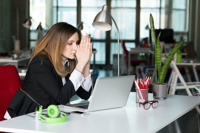 Business Person thinking hard in blessing hands Gesture at grey Desk with Computer and other Electronics in contemporary digital corporate Office Interior. Business Person thinking hard in blessing hands Gesture at grey Desk with Computer and other Electronics in contemporary digital corporate Office Interior