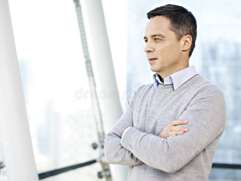 Caucasian businessman in casual wear standing and thinking by the windows in office. Caucasian businessman in casual wear standing and thinking by the windows in office.