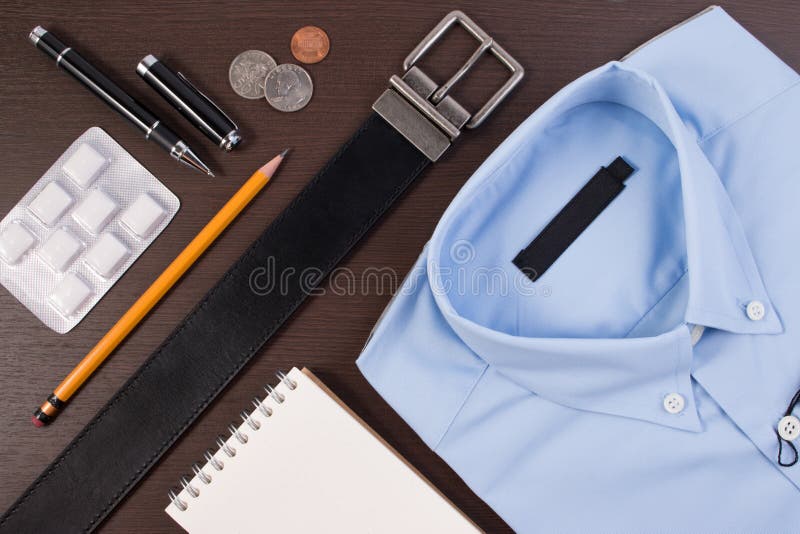 Business shirt casual outfit and accessory belt with pen and chewing gum on wooden table. royalty free stock image Business shirt casual outfit and accessory belt with pen and chewing gum on wooden table. royalty free stock image