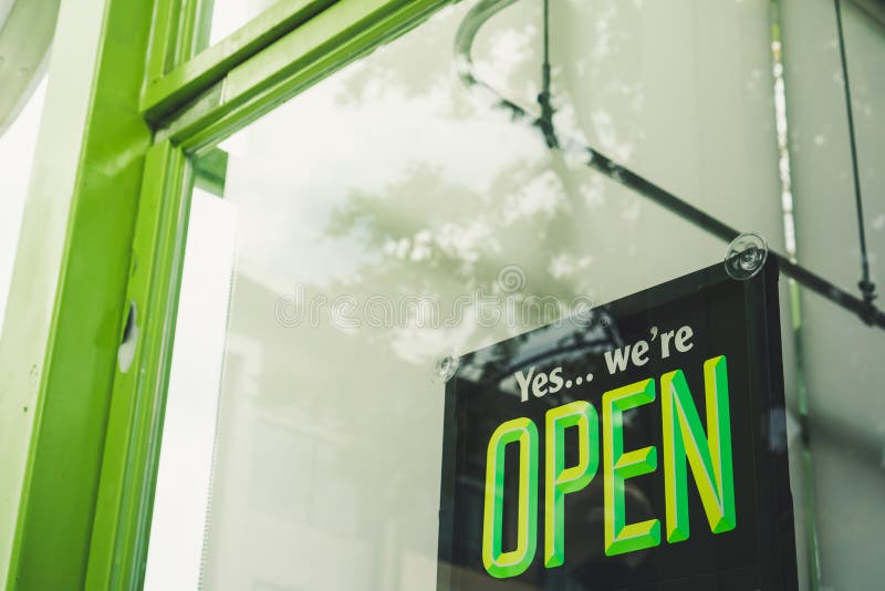 A business sign that says â€˜Openâ€™ on cafe or restaurant hang on door at entrance.