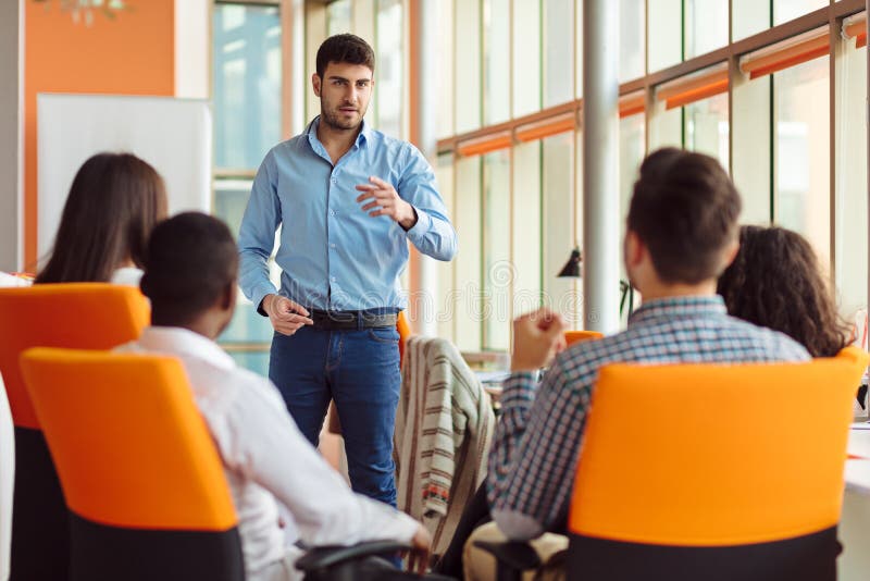 Business, startup, presentation, strategy and people concept - man making presentation to creative team at office stock images