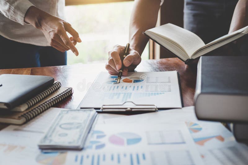 Business team are meeting and discussing marketing plan and pointing graph report analyzing financial figures denoting royalty free stock images
