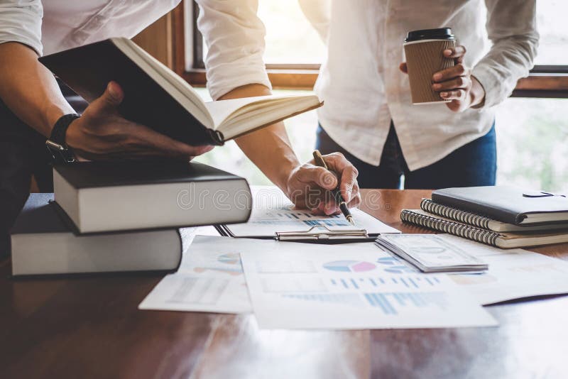 Business team are meeting and discussing marketing plan and pointing graph report analyzing financial figures denoting royalty free stock photo