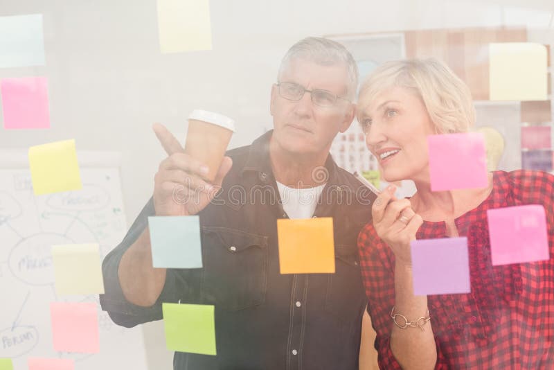 Business team pointing post its on the wall royalty free stock photography Business team pointing post its on the wall royalty free stock photography