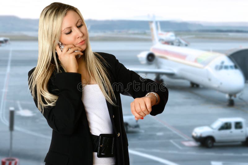 Caucasica donna d'affari guardando il suo orologio, nella sala partenze di un aeroporto, in attesa di prendere il suo volo per il suo viaggio di lavoro.