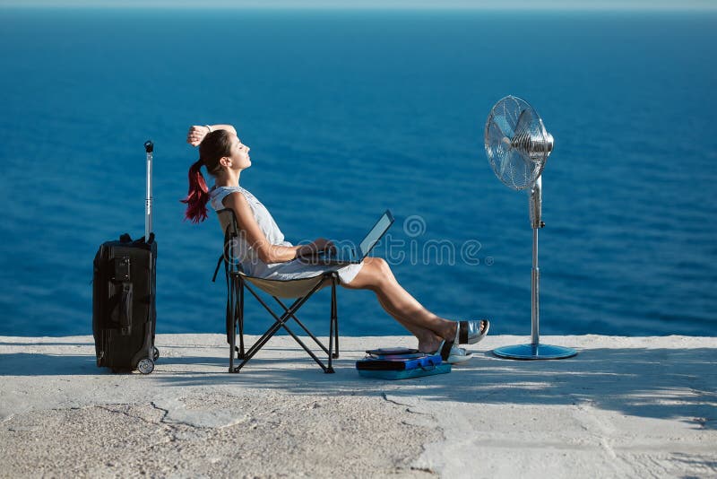 Business travelling, life work balance concept. Woman working on laptop and relaxing on seashore. Lifestyle change idea.