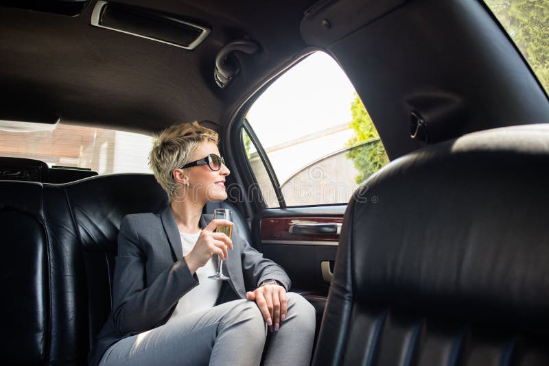 Business woman with glass of champagne in limousine