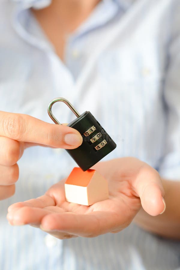 Business woman holding a cipher lock on the roof of a miniature house, symbolizing the concept of home security or insurance royalty free stock photography Business woman holding a cipher lock on the roof of a miniature house, symbolizing the concept of home security or insurance royalty free stock photography