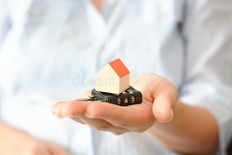 Business woman holding a cipher lock under a miniature house, symbolizing the concept of home security or insurance stock photos Business woman holding a cipher lock under a miniature house, symbolizing the concept of home security or insurance stock photos