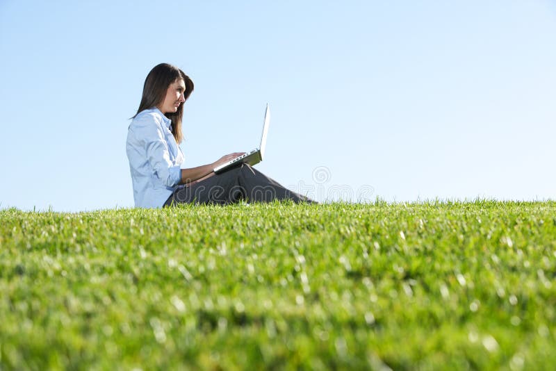 A business woman on a laptop in a field