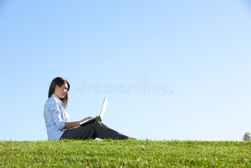 A business woman on a laptop in a field