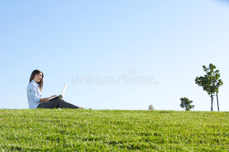 A business woman on a laptop in a field