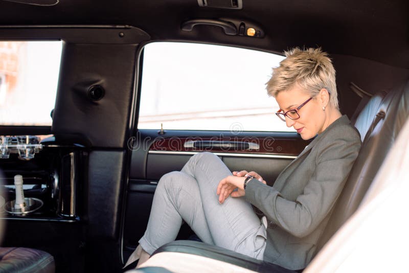 Business woman looking at watch in limousine