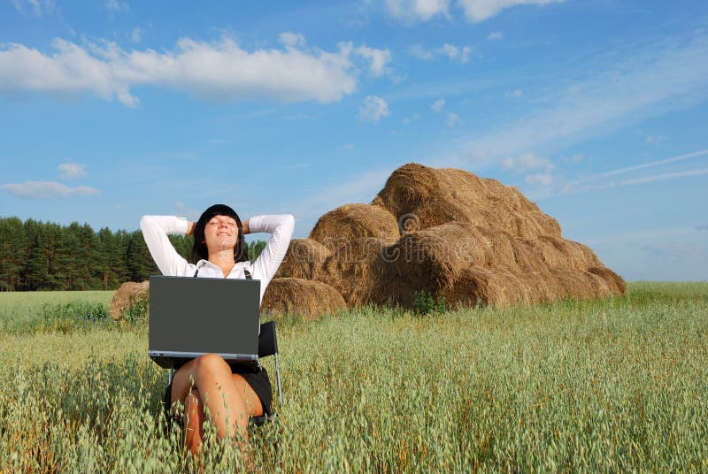 Young attractive girl with laptop on rural field. Young attractive girl with laptop on rural field