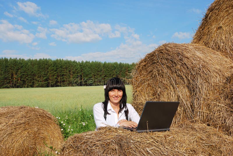 Young attractive girl with laptop on agricultural field. Young attractive girl with laptop on agricultural field