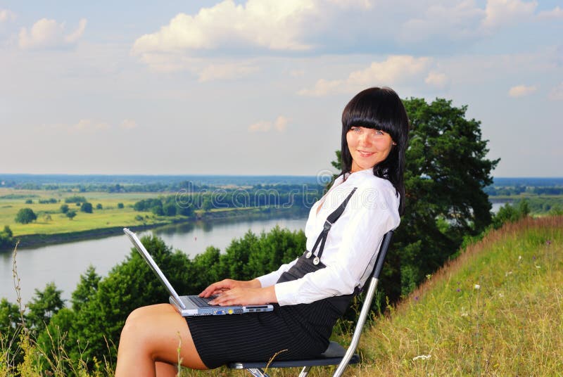 Attractive young girl working on computer in nature. Attractive young girl working on computer in nature