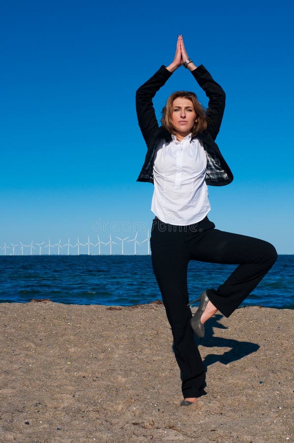 Business woman standing in yoga pose on the beach