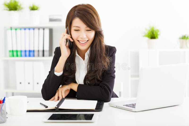 Happy business woman talking on the phone in office