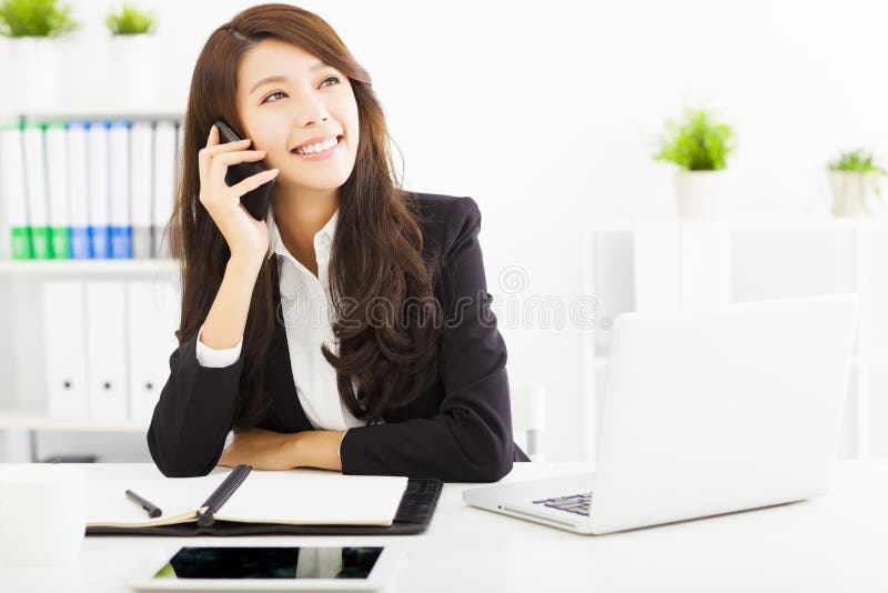 Happy business woman talking on the phone in office