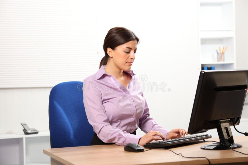 Business woman typing at computer in office