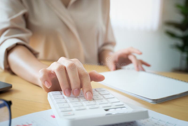 Business woman using calculator to review balance sheet annual using document and laptop computer to calculating budget stock photos