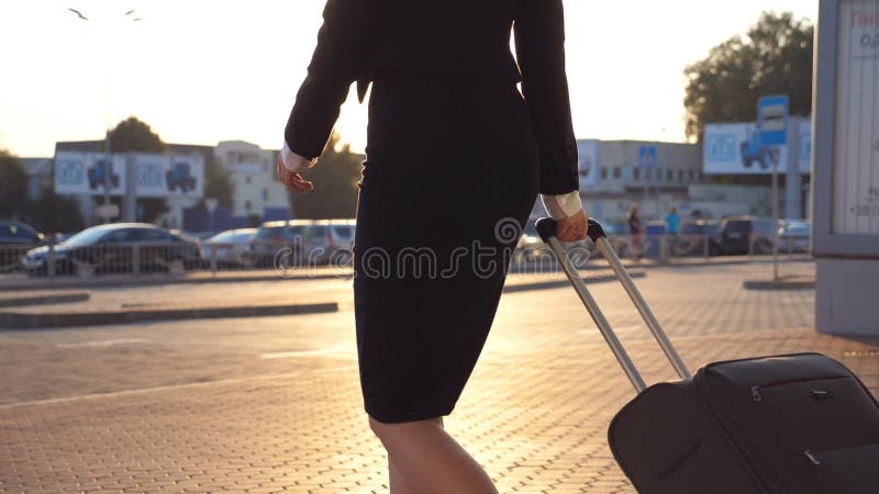 Business woman walking with her suitcase from airport hall or waiting room. Young girl in heels going from terminal and