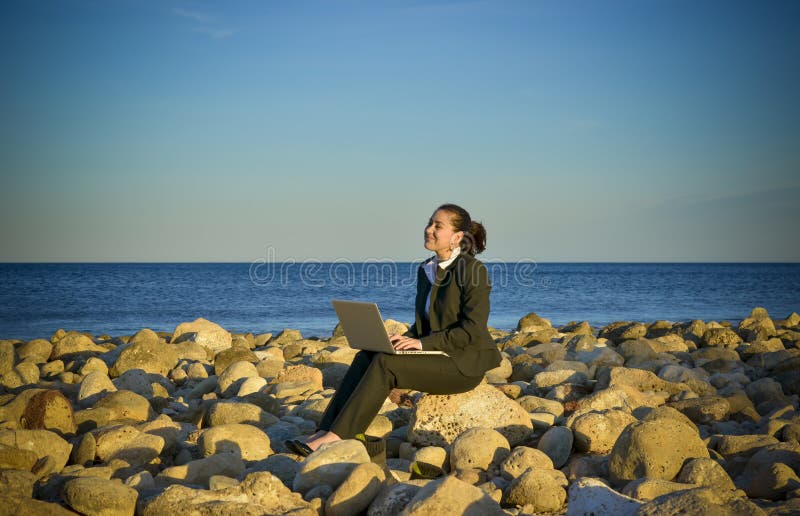 Business woman working on laptop at the beach