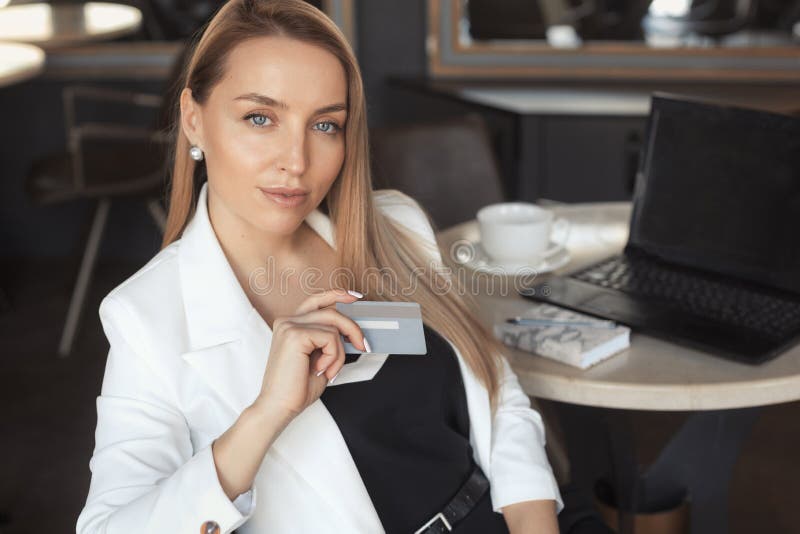 Business woman working with laptop in cafe, holging credit card