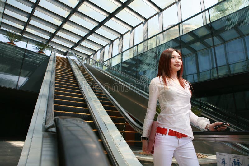 Business women holding mobile phone on escalator