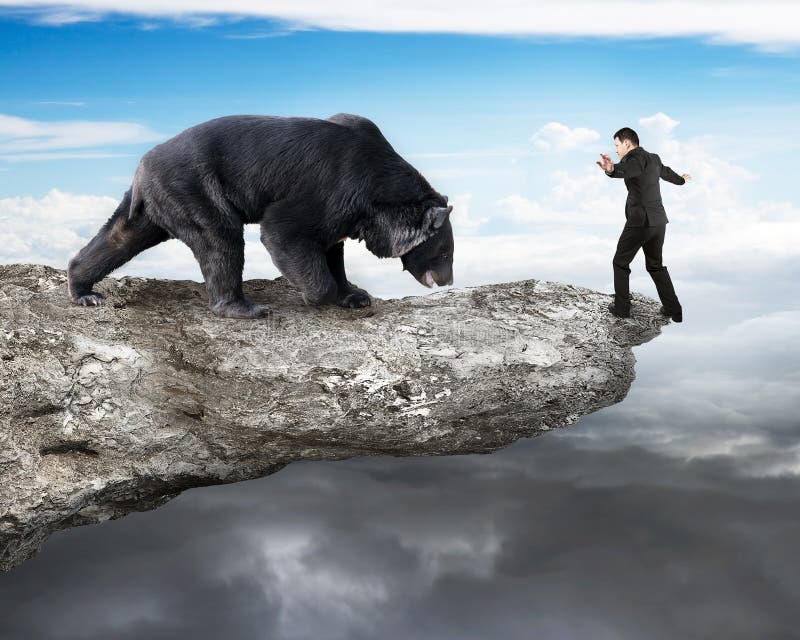 Businessman against black bear balancing on cliff with sky cloud stock photos