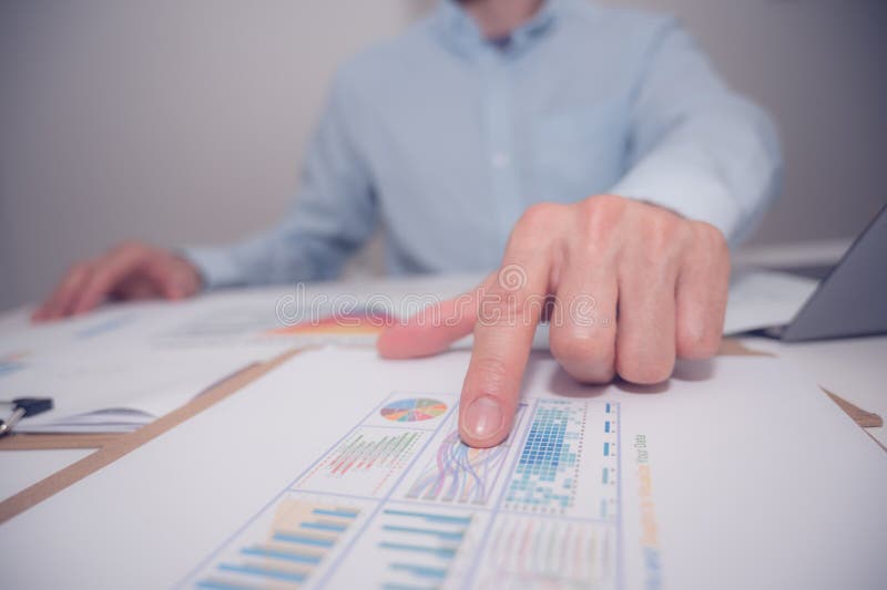 Businessman or analyst pointing at paperwork on a board room table at a business presentation stock photography