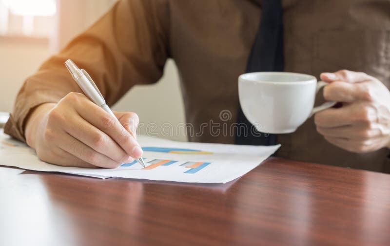 Businessman analyzing graph document and holding coffee in office stock photos