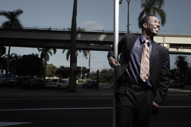 Businessman with arm around a pole