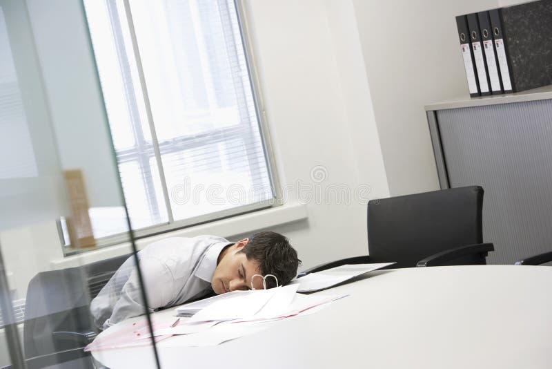 Businessman asleep at desk by scattered files in the office. Businessman asleep at desk by scattered files in the office