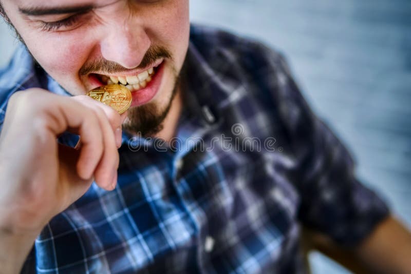 Businessman bites a golden bitcoin for checks authenticity with his teeth royalty free stock images