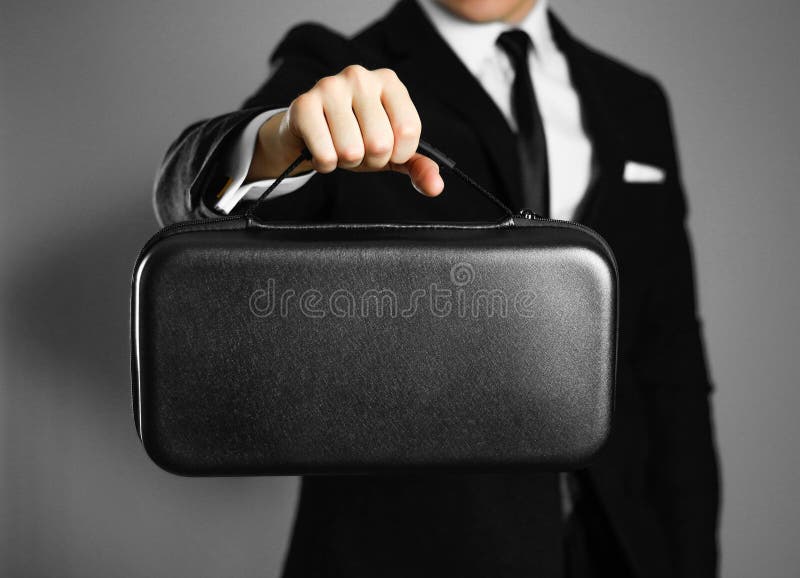 Businessman in a black suit holding a black leather bag. Close up. Isolated background royalty free stock images Businessman in a black suit holding a black leather bag. Close up. Isolated background royalty free stock images