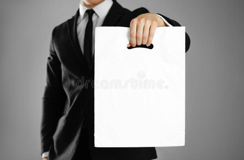 Businessman in a black suit holding a white plastic bag. Close up. background stock images Businessman in a black suit holding a white plastic bag. Close up. background stock images