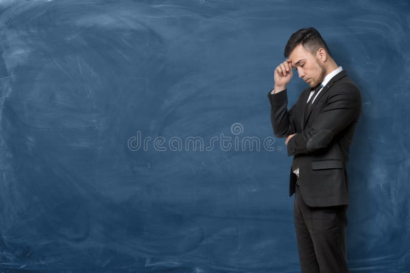 Businessman in black suit standing with his hand on forehead stock photo Businessman in black suit standing with his hand on forehead stock photo