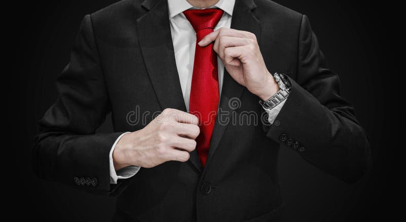 Businessman in black suit tying red necktie on black background royalty free stock image Businessman in black suit tying red necktie on black background royalty free stock image