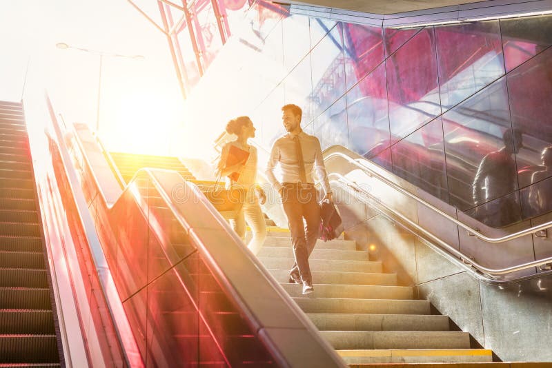 Businessman and businesswoman talking while walking down stairs with lens flare in background stock photography Businessman and businesswoman talking while walking down stairs with lens flare in background stock photography