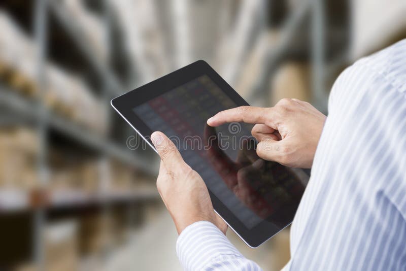 Uomo d'affari di controllo di inventario nel magazzino di un'azienda di produzione su tablet touchscreen.