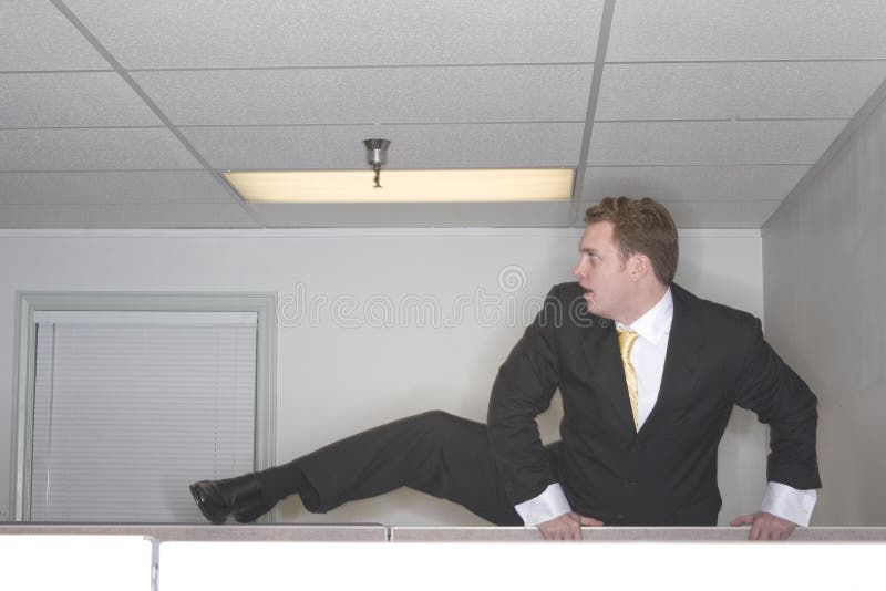 Businessman climbs over cubicl