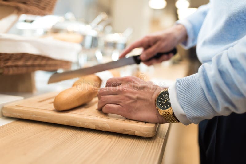 Businessman with golden watch on his hand Cut baguette for his breakfast. Businessman with golden watch on his hand Cut baguette for his breakfast